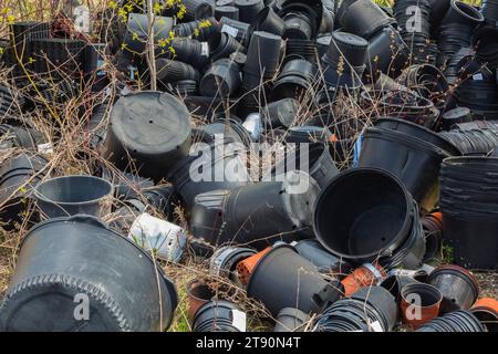 Stapel aussortierter schwarzer Kunststoffbehälter, die zum Anpflanzen von Pflanzen im Gartencenter verwendet werden. Stockfoto