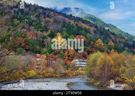 Kollaborationsszene der Hodaka Bergketten, das unidentifizierte Bergresort Hotel im Hintergrund des Flusses Azusa und farbenfrohe Herbstbäume Stockfoto