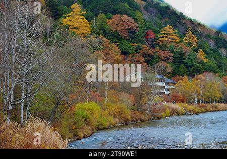 Kollaborationsszene der Hodaka Bergketten, das unidentifizierte Bergresort Hotel im Hintergrund des Flusses Azusa und farbenfrohe Herbstbäume Stockfoto