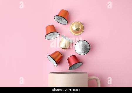 Viele Kaffeekapseln und Tasse auf rosafarbenem Hintergrund, Draufsicht Stockfoto