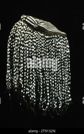 Kopfbedeckung, 20. Jahrhundert, 12,25 x 6,5 Zoll (31,1 x 16,5 cm), Baumwolle, Quasten, Metallquasten, Niger, im 20. Jahrhundert wurde der Gorowije ine Hut seit Jahrhunderten von Dogon-Männern in Mali getragen. Diese Hüte bestehen aus lokal gewebtem Streifentuch, gefärbt mit Indigo- oder Ohrenbraunen Pigmenten, mit verdrehten Baumwollbindern an den Seiten und auf der Rückseite der Krone. Dieser Hut hat auch dünne Aluminiumstreifen als Dekoration Stockfoto