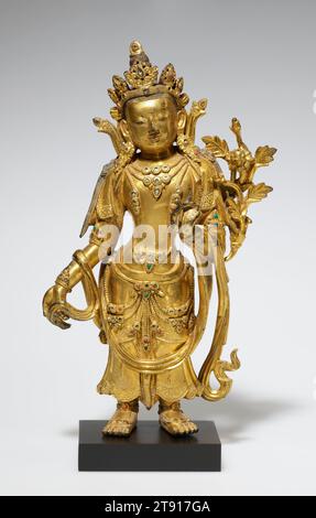 Bodhisattva, eins von einem Paar, 18. Jahrhundert, 9 1/2 x 4 3/4 x 2 Zoll. (24,1 x 12,1 x 5,1 cm), vergoldete Bronze, China, 18. Jahrhundert, obwohl sie sich spiegelbildlich darstellen, stellen diese beiden Statuen wahrscheinlich nicht den gleichen Bodhisattva dar; sie sind wahrscheinlich eher die beliebten Götter Maitraya und Avalokitesvara. Sie standen in anmutiger Haltung und hielten den Stiel einer Lotusblume und bildeten wahrscheinlich Teil einer skulpturalen Triade, die ein größeres Bronzebild des Buddha flankierte Stockfoto
