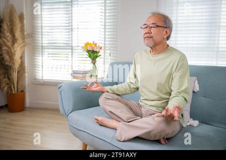 Ein alter asiatischer Mann übt Yoga und Meditation in Lotusposition und mit geschlossenen Augen Stockfoto