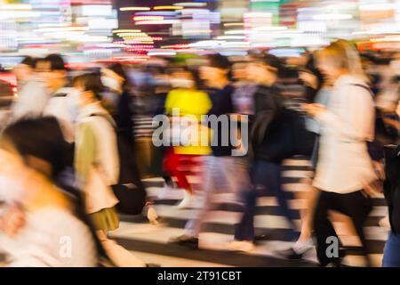 Abstraktes Foto einer Menschenmenge, die nachts eine Straße in der Großstadt überquert Stockfoto
