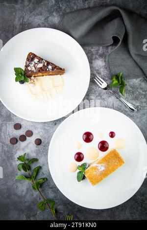 Weißer Biskuitkuchen mit Tropfen Sirup, Minze und Waldbeeren auf einer runden Platte Stockfoto