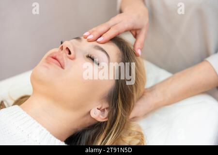 Heiler mit leicht berührten 32 Zugangspunkten auf dem Kopf der Frau, die positive Gedanken und Emotionen zur Veränderung stimulieren. Alternative Stockfoto