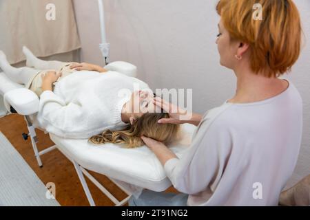 Heilerin mit leicht berührten 32 Zugangspunkten auf dem Kopf der Frau, die positive Gedanken und Emotionen zur Veränderung stimulieren Stockfoto