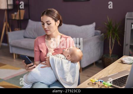 Porträt einer jungen Mutter mit schlafendem Baby und Smartphone zu Hause, Kopierraum Stockfoto