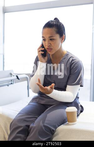 Birassische Ärztin, die im Krankenhaus auf dem Smartphone spricht Stockfoto