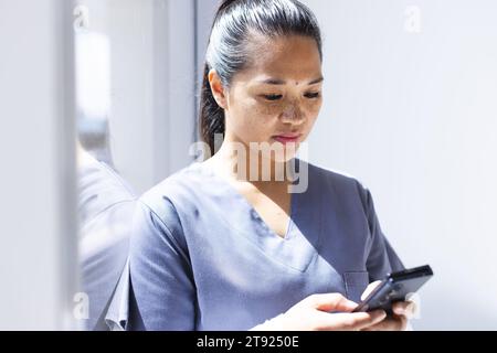 Birassische Ärztin mit Smartphon im Krankenhaus. Medizin, Gesundheitswesen, Kommunikation, Arbeit und Krankenhaus, unverändert. Stockfoto