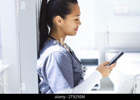 Birassische Ärztin mit Smartphon im Krankenhaus. Medizin, Gesundheitswesen, Kommunikation, Arbeit und Krankenhaus, unverändert. Stockfoto