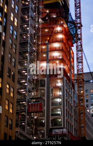 Ein Wolkenkratzer in New York City im Bau, ein Gebäude, das in der Abenddämmerung mit Gerüsten bedeckt ist, in Manhattan mit einem Baukran in der Nacht Stockfoto