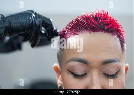 Der Friseur färbt das Haar einer Asiatin in Rosa. Kurzer, extremer Haarschnitt. Stockfoto