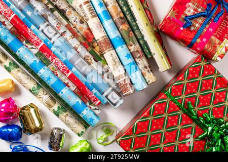Mehrere Rollen Geschenkpapier, festlich, Geschenkbänder, Pakete, weißer Hintergrund Stockfoto