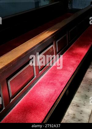 Teil einer Bank mit einem roten sitzkissen im Sonnenlicht Stockfoto