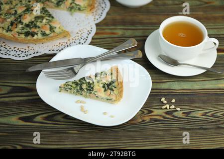 Köstlicher Quiche-Kuchen mit Lachsfischen und Pinienkerne-Füllung. Frühstück mit Quiche und einer Tasse Tee Stockfoto