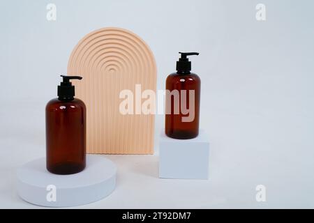 Komposition mit geometrischen Formen und Naturkosmetik. Glasflaschen mit Spender auf hellgrauem Hintergrund. Stockfoto