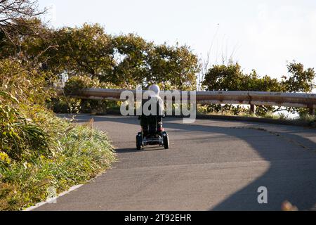 Eine ältere Frau, die in Japan ein elektrisches Mobilitätsfahrzeug fährt. Stockfoto