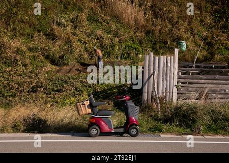 Eine ältere Frau, die in Japan ein elektrisches Mobilitätsfahrzeug fährt. Stockfoto