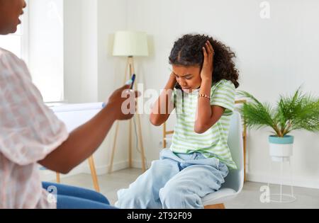 Frustriertes, verwirrtes Teenager-Mädchen, das in der Schule vor dem Lehrer sitzt. Stockfoto