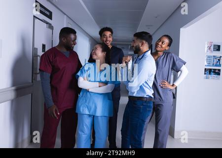 Glückliche verschiedene männliche und weibliche Ärzte sprechen im Krankenhauskorridor Stockfoto