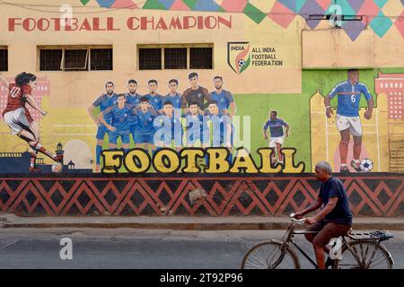 Ein Radfahrer kommt an einem Wandbild in Byculla, Mumbai, Indien vorbei, das den Fußballweltmeister 2022 in Argentinien zeigt Stockfoto