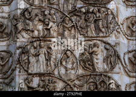 Teil der Marmorplatte mit Basreliefen, die Szenen aus dem Neuen Testament und dem Leben von Maria und Jesus an der Westfront der Kathedrale in Orvieto, Umbrien, Italien, im Duomo di Santa Maria Assunta darstellt. Die Skulptur, die die Westfront bereichert, wurde von einem Team unter der Leitung des italienischen Architekten und Bildhauers Lorenzo Maitani (ca. 1275–1330) ausgeführt. Die Szenen in diesem Detail beinhalten Jesu triumphalen Eintritt in Jerusalem (oben links) und Judas’ Verrat an Christus mit einem Kuss (oben rechts). Stockfoto