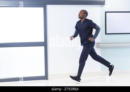 afroamerikaner, männlicher Arzt, der im Krankenhaus durch den Korridor läuft, Kopierraum. Medizin, Gesundheitswesen, Arbeit und Krankenhaus, unverändert. Stockfoto