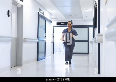 Birassische Ärztin, die im Krankenhaus durch den Korridor läuft, Kopierraum Stockfoto