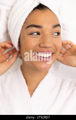 Glückliche Frau im Bademantel und mit Handtuch an der weißen Wand. Lebensstil, Selbstversorgung und häusliches Leben unverändert. Stockfoto