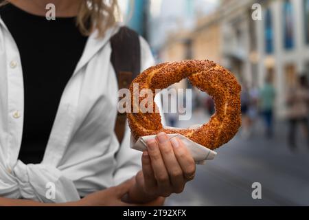 Frau hält eine Nahaufnahme eines traditionellen türkischen Bagel-Simit auf der Straße. Türkisches Fast Food. Stockfoto