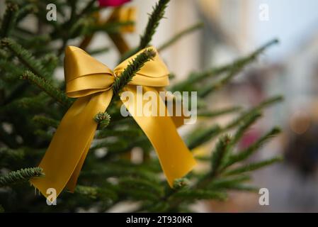 Tauchen Sie ein in die Weihnachtsstimmung mit einem Blick auf einen Weihnachtsbaum, der von einem leuchtenden goldenen Band geschmückt ist, vor einem traumhaften und verschwommenen Hintergrund Stockfoto