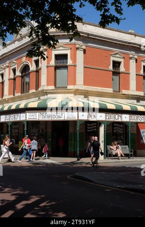 New Edition Bookshop, Fremantle, ein spätviktorianisches Gebäude mit gestreiftem gewelltem Vordach mit gusseisernen Säulen und Verandahalterungen bei voller Sonne Stockfoto