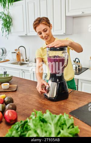 Die vegetarische Frau mahlt frisches Obst im elektrischen Mixer, köstliches Smoothie-Rezept Stockfoto