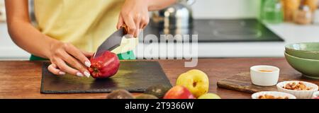 Zugeschnittene Ansicht einer Frau, die Apfel in der Nähe reifer Früchte und verschiedener vegetarischer Zutaten schneidet, Banner Stockfoto