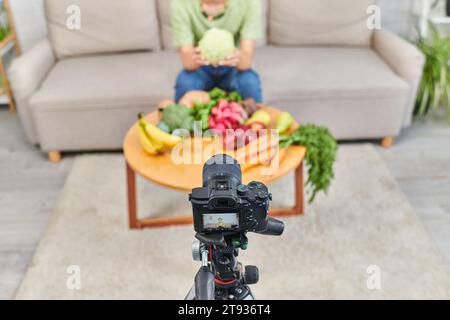 Hochwinkelansicht der Digitalkamera in der Nähe einer zugeschnittenen Frau mit Produkten pflanzlichen Ursprungs während des Video-Blogs Stockfoto