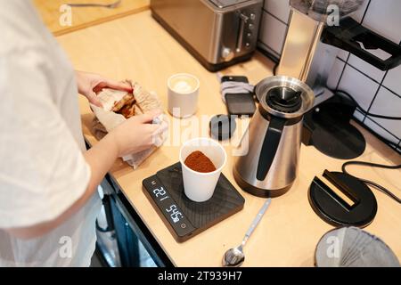Nahaufnahme der Hände eines nicht erkennbaren Barista, der Kaffee auf einer Präzisionswaage in einem modernen spezialisierten Café wiegt Stockfoto