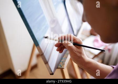 Nahaufnahme eines nicht erkennbaren Frauenhandgemäldes mit einem Pinsel auf Leinwand Stockfoto