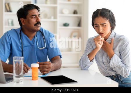 Kranke Junge Indische Frau Hustet Beim Treffen Mit Dem Männlichen Arzt In Der Klinik Stockfoto