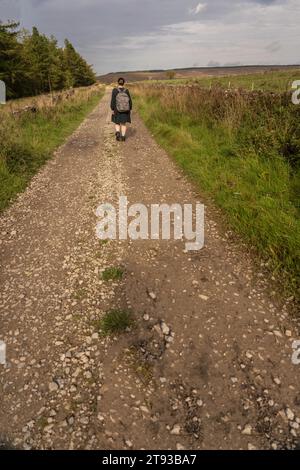 Ein Mädchen im Kleid, das vor der Kamera auf einem matschigen, nassen Pfad in Osmotherly, North Yorkshire, England, Großbritannien, läuft Stockfoto