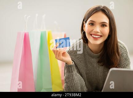 Positive junge Frau, die von zu Hause aus online kauft Stockfoto