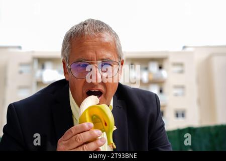 Business Digital Nomad isst eine Banane bei der Arbeit. Arbeitspause zum Mittagessen Stockfoto