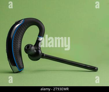 Nahaufnahme eines Bluetooth-Headsets auf grünem Hintergrund und Kopierbereich Stockfoto