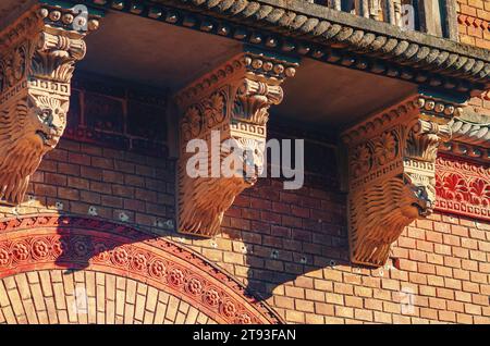 Elemente der architektonischen Dekoration von Gebäuden, ein Balken unter dem Balkon aus Löwenköpfen, Gipsmuster und Stuck. Stockfoto