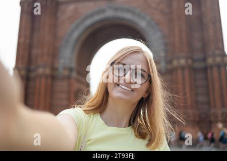 Frau macht Selfie gegen die erstaunliche Architektur des Arc de Triomf-Tores in Barcelona Stockfoto