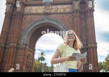 Blick auf attraktive junge weibliche Touristen, die die neue Stadt erkunden. Frau mit einer Papierkarte über zentrale Frau, die Selfie gegen erstaunliche Architektur macht Stockfoto