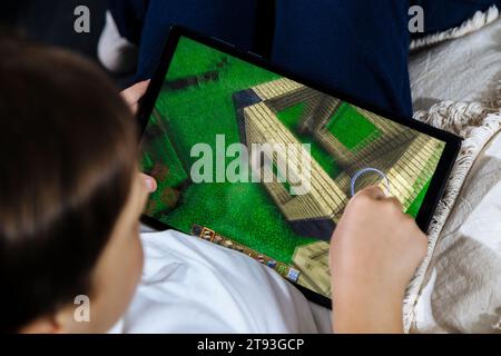 Kleiner Junge, der Minecraft-Spiel auf einem Tablet spielt. Minecraft ist ein sehr beliebtes Spiel bei Kindern und Jugendlichen. Rosario, Argentinien - 20. November 2023. Stockfoto