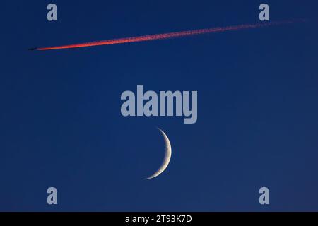 Blauer Himmel mit Mond und fliegendem Flugzeug Stockfoto