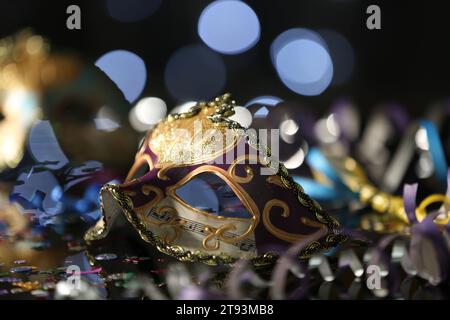 Schöne Karnevalsmaske auf dem Tisch gegen verschwommenes Licht Stockfoto