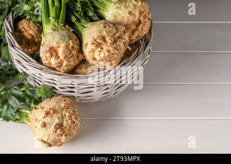 Frische rohe Selleriwurzeln im Korb auf weißem Holztisch. Leerzeichen für Text Stockfoto